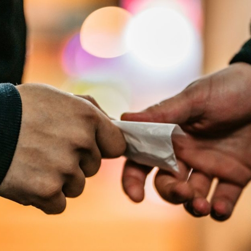 a person handing over drugs to another person